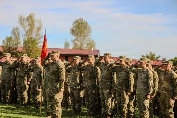 Utah National Guard Soldiers in formation saluting behind the unit guidon flag outdoors