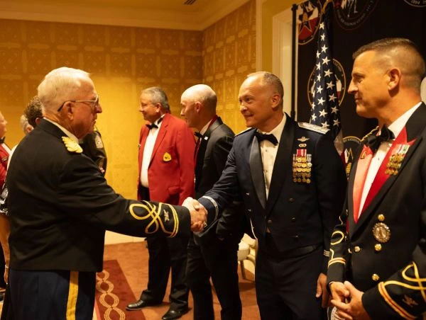 Two decorated servicemembers greet guests at a formal event