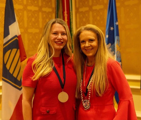 Two women in red dresses pose for a photo at a formal event
