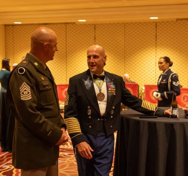 Two decorated servicemembers converse at a formal event