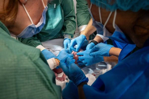 A team of medical caretakers attends to a newborn infant