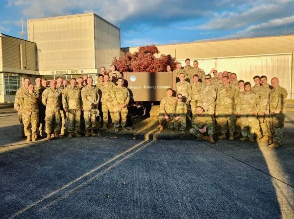 Servicemembers pose for a photo in front of a building