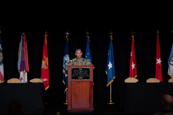 General Okamura giving a speech behind a podium with flags lined up behind him