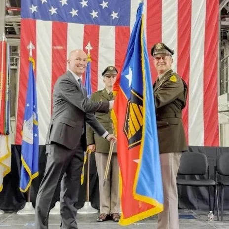 A governor hands a flag to a general officer