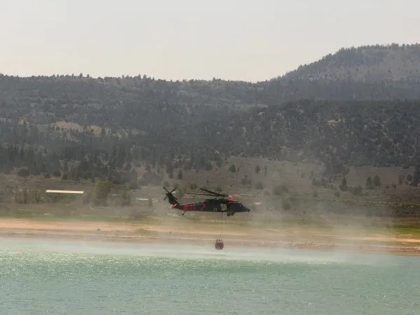A helicopter fills a bucket of water from a reservoir