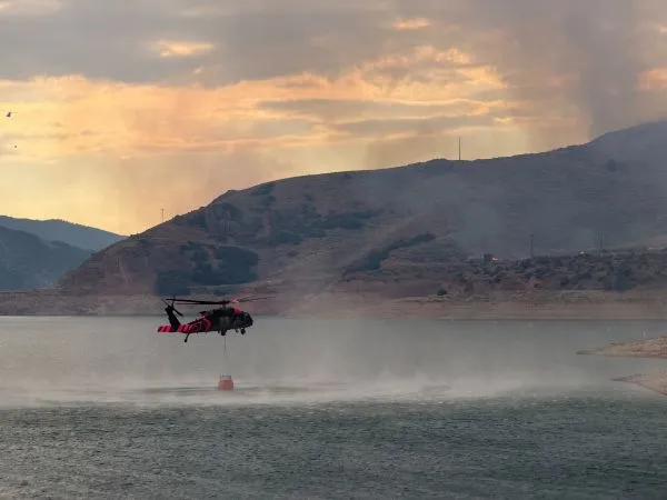 A helicopter filling a bucket of water from a reservoir
