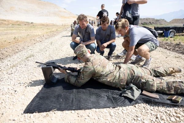 Soldier showing the kids how they shoot laying down