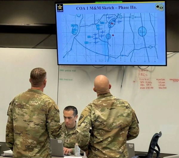 Servicemembers review a map on a screen in a classroom