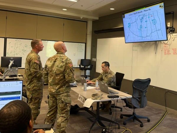Servicemembers look at a screen in a classroom