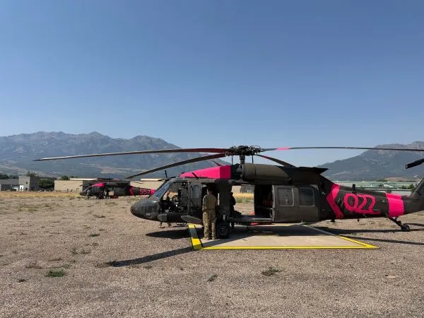 Two helicopters and crewmen at a staging area