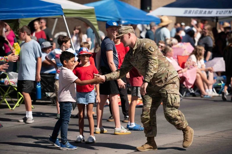 soldier walking in parade shaking hands with kid
