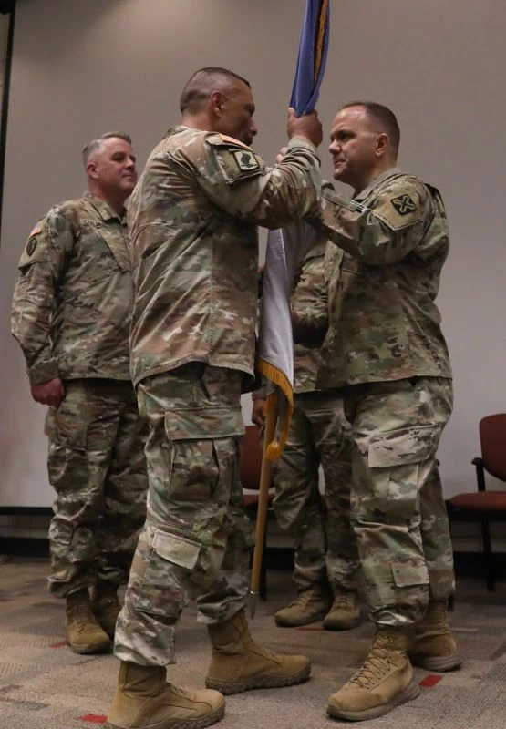 Servicemembers pass a military flag in a ceremony