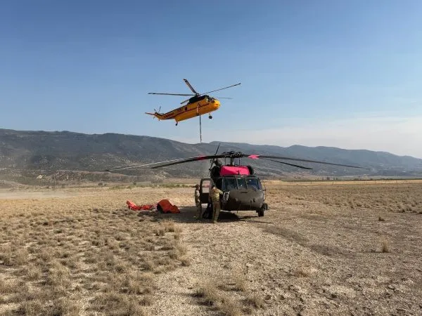 One helicopter flying over another helicopter staged on the ground