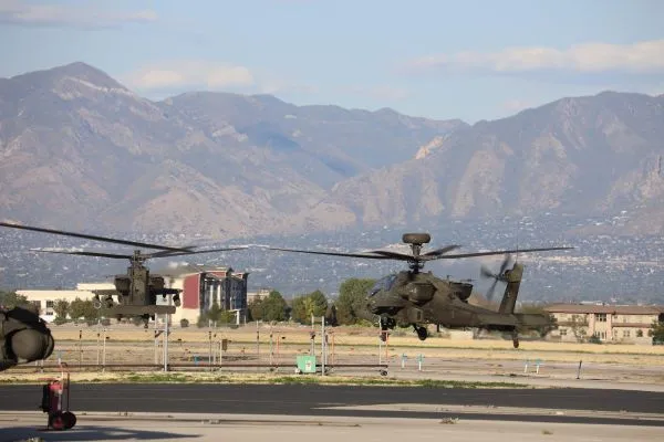 Two military helicopters taking off a runway