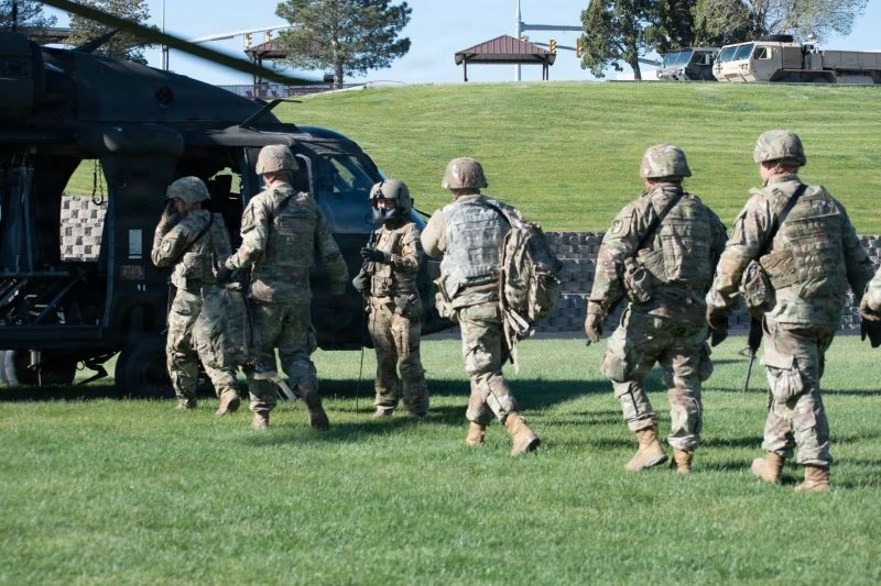 Servicemembers board a medical helicopter on a grassy field