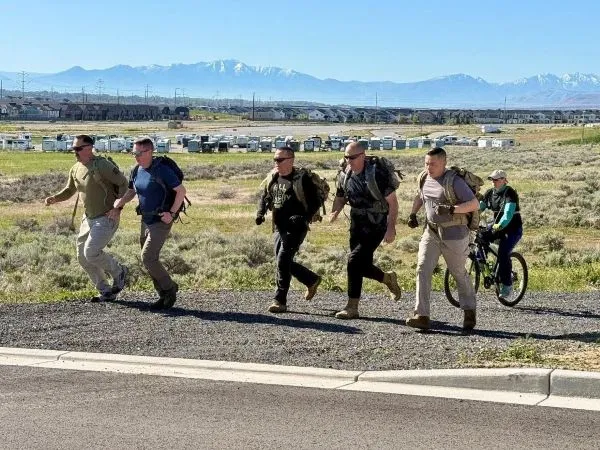 Five individuals run with a biker following along a gravel path