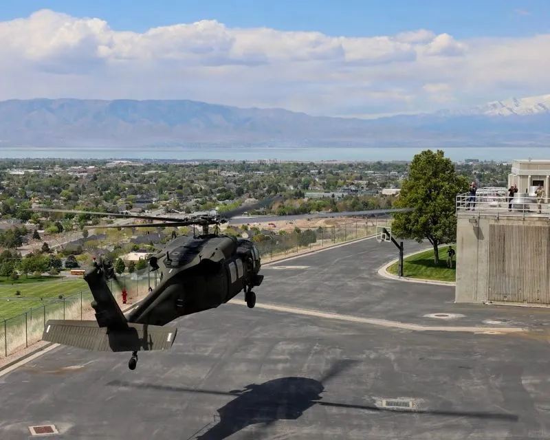 A military helicopter lands on a blacktop surface