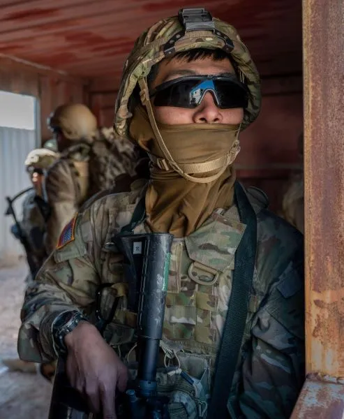A soldier stands ready, wearing protective gear and a rifle