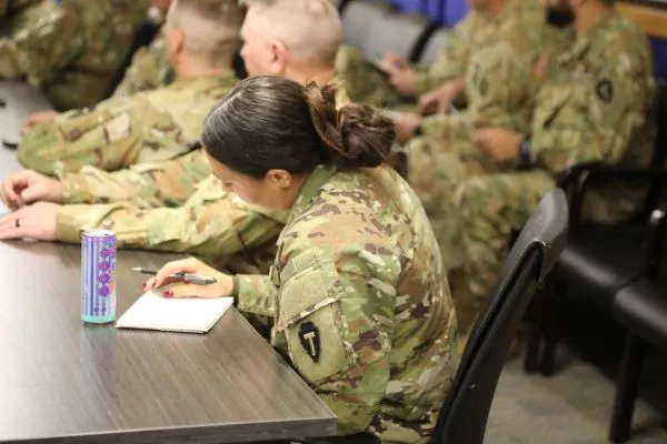 A soldier writing notes during a meeting
