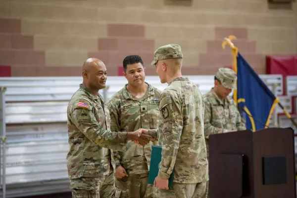 A high-ranking military official shakes hands with a Soldier
