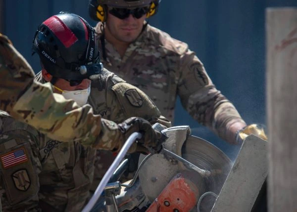 Servicemembers cut concrete with a metal saw