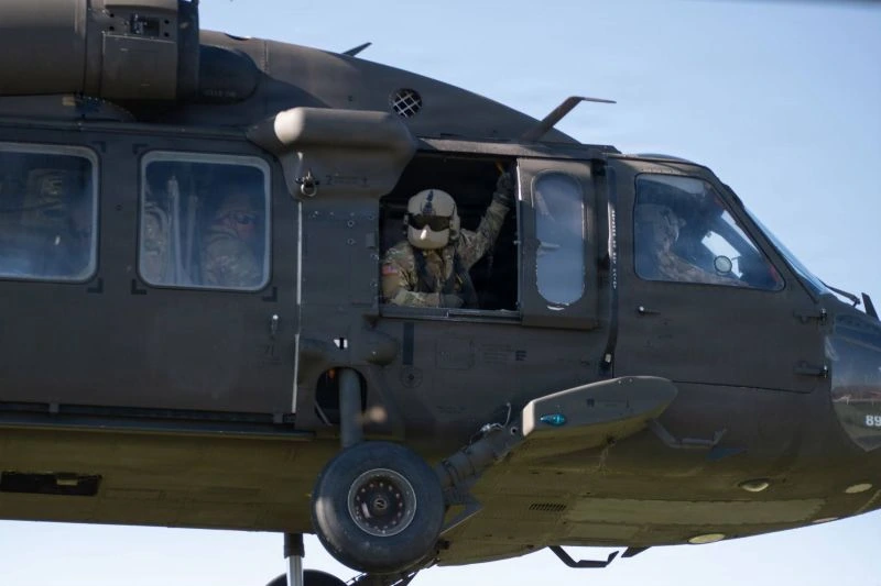 A crew chief looks out the window of a hovering medical helicopter