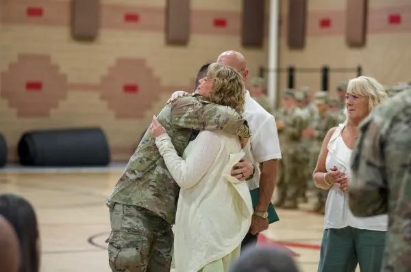 A soldier in uniform hugging a woman