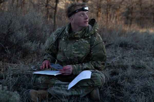 A soldier reviews a map at dusk