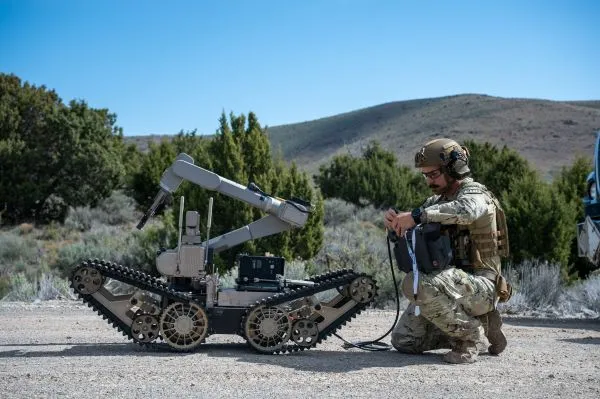 An airman inspects a robot