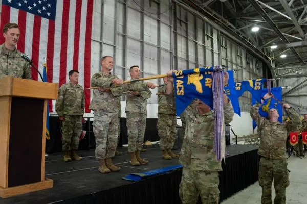 Utah Air National Guard service members unfurling blue military guidons on stage during a cyberspace operations redesignation ceremony